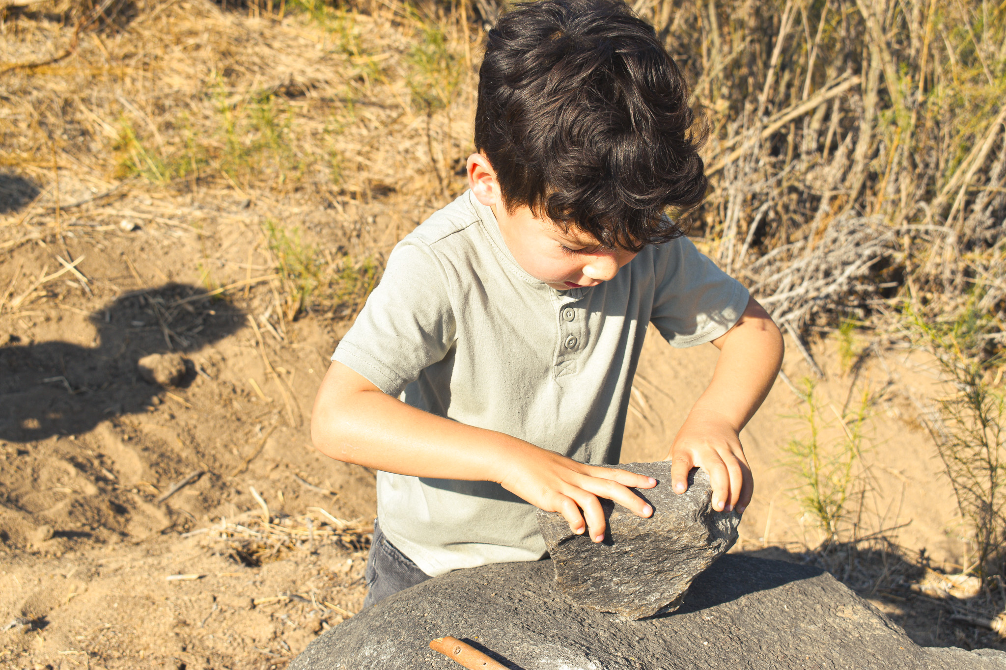 Child examining a rock closely in golden afternoon light